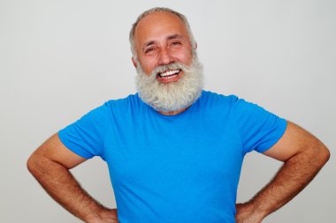 Yakışıklı yaşlı adam kalçalarında elleri ile ayakta ve gülümseyen