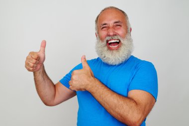 Neşeli yaşlı adam içtenlikle gülümseyen ve iki başparmak kadar veren