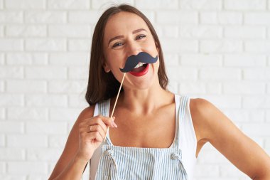 Bıyık maskesi tutan ve gülümseyen gülümseyen kadın