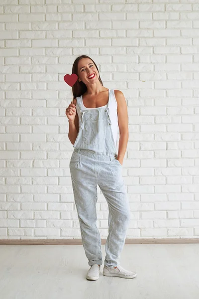 Mulher bonita feliz de pé e segurando coração papel vermelho perto — Fotografia de Stock