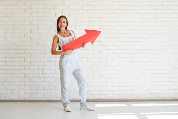 Pretty woman is holding big red paper arrow — Stock Photo, Image