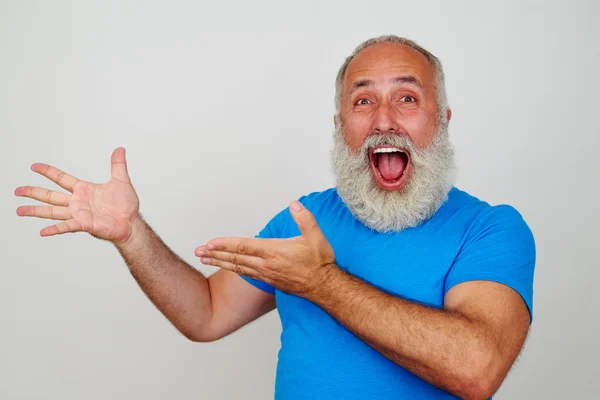 Senior white-bearded man delighted and pointing at something wit — Stock Photo, Image