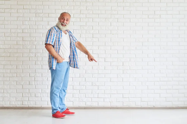 Glimlachend Senior is wijst zijn vinger naar de vloer — Stockfoto