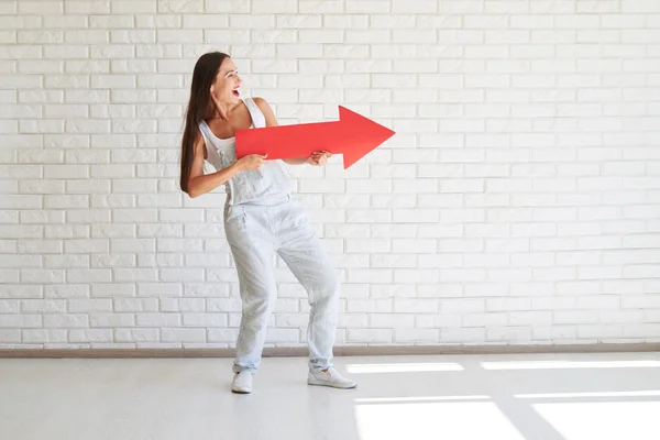 Sonriente guapa morena se para y sostiene una gran flecha roja y un baño —  Fotos de Stock