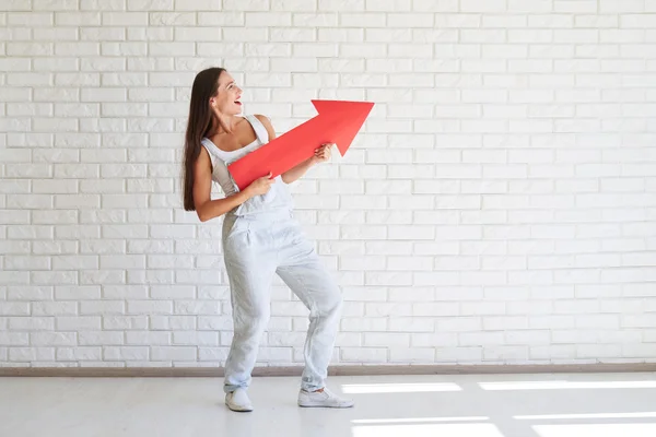 Mujer sonriente se para sosteniendo una gran flecha roja y mirando hacia otro lado —  Fotos de Stock