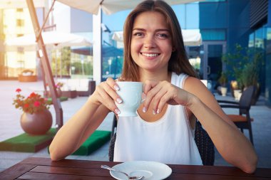 Kafede oturan ve bir fincan içme genç iş kadını bir