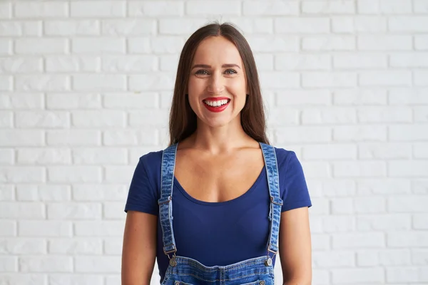 Giovane donna sorridente in piedi contro un muro — Foto Stock