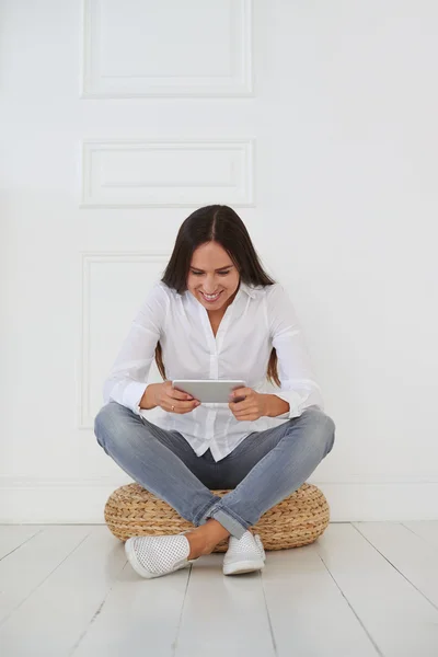 En kvinna som sitter på en fotpall och använder en digital tablett — Stockfoto