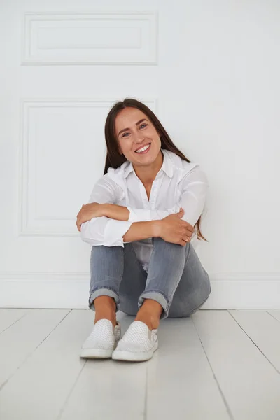 Casual vrolijke jonge vrouw zittend op de vloer — Stockfoto