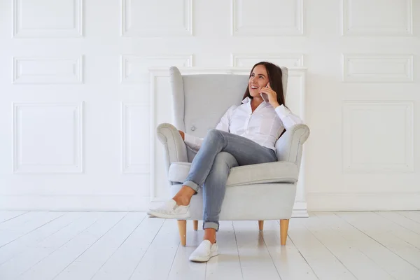 Frau spricht im Sessel auf dem Smartphone — Stockfoto