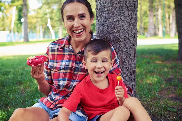 Moderne junge Mutter und ihr Sohn zeigen sich glücklich bei einem Spaziergang — Stockfoto