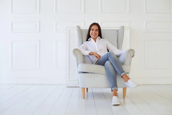 Mooie vrouw geniet van gezellige sfeer terwijl zittend op de armcha — Stockfoto