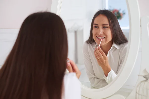 Reflection of young beautiful woman putting on lipstick — Stock Photo, Image