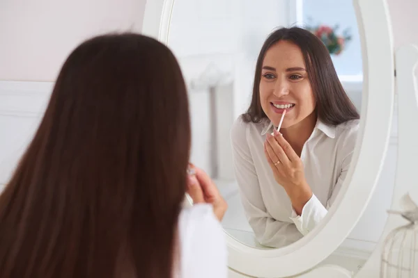 Spiegelbild einer jungen schönen Frau, die Lippenstift aufsetzt — Stockfoto