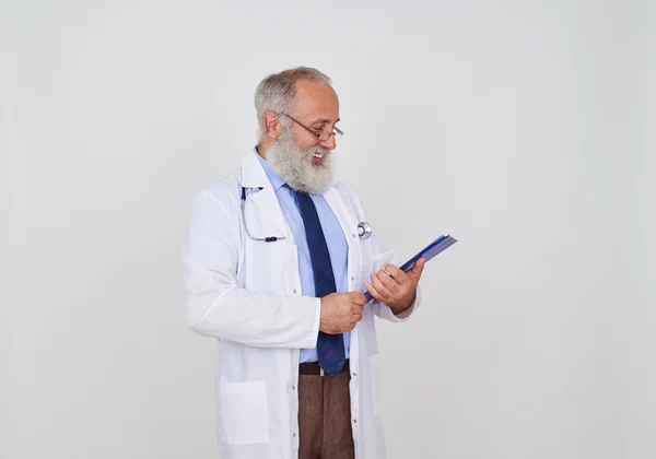 Sonriente médico maduro barbudo mirando atentamente en una carpeta — Foto de Stock