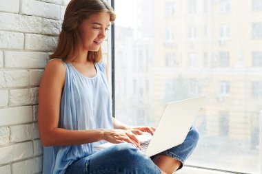  Evde oturan ve bir lapt üzerinde çalışan modern bir kızın yakın çekim
