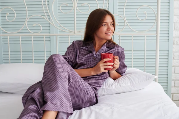 Hermosa mujer mirando por la ventana mientras está acostada en su cama — Foto de Stock