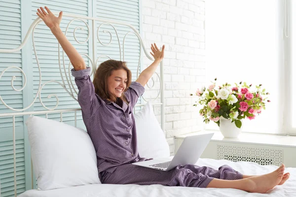 Vrolijke vrouw in pyjama aan het bed met handen opgeheven en l — Stockfoto