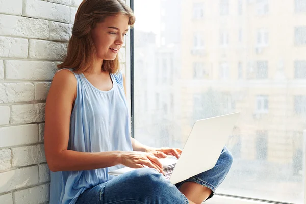 Primo piano di una ragazza moderna seduta a casa e che lavora su un lapt — Foto Stock