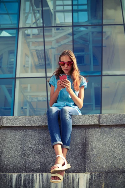 Una giovane ragazza moderna controlla l'e-mail tramite smartphone mentre è seduta — Foto Stock