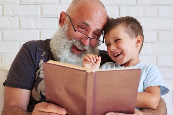 Bearded aged man and his grandson having fun reading a book toge — Stock Photo, Image
