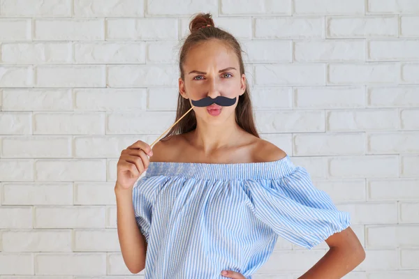 Cool seriös tjej som håller kul papper mustasch hållande hand på en h — Stockfoto