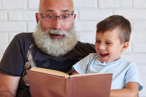 Grandfather and his grandson spending time together reading a fu — Stock Photo, Image