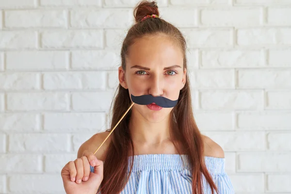 Fröhliches Mädchen, das mit Papierschnurrbart auf einem Stock spielt — Stockfoto