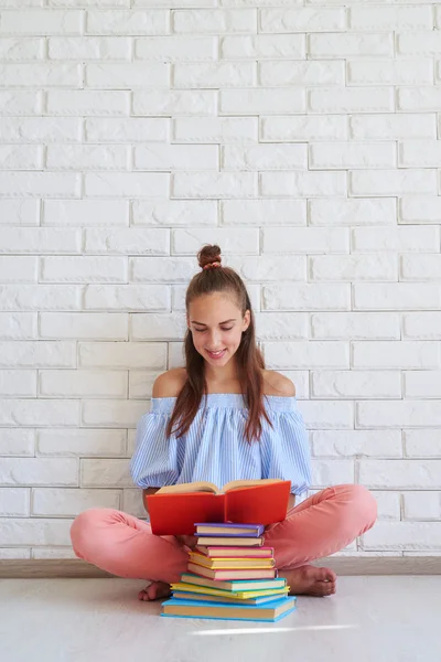 Расслабленная девушка читает книгу, сидя на полу — стоковое фото
