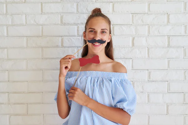 Серйозна в той же час задоволена дівчина тримає паперові вуса — стокове фото