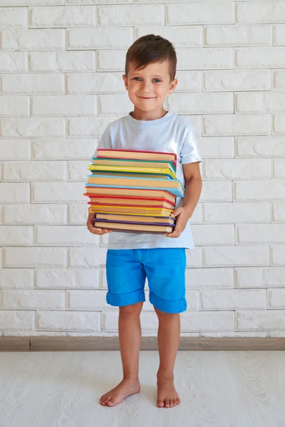 Kicsi értelmes fiú tartó egy cölöp-ból könyv — Stock Fotó