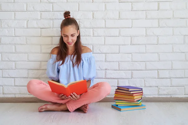 Jovem morena do sexo feminino relaxante no chão enquanto lê um livro — Fotografia de Stock