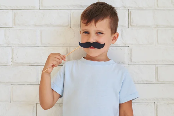 Young gentleman holding paper moustache with rather shrewd look — Φωτογραφία Αρχείου