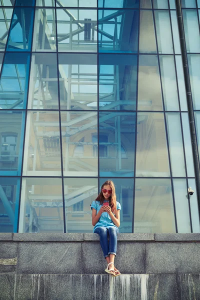 Молодая женщина в солнечных очках сидит на улице и смотрит на нее с — стоковое фото