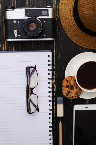 Primer plano del sombrero, bloc de notas, cámara, teléfono, anteojos y una taza o —  Fotos de Stock