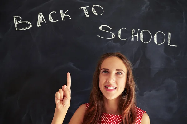 Primo piano di affascinante studentessa sorridente che punta a scho — Foto Stock