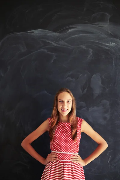 Sonriente adolescente de pie con las manos en las caderas contra el blackbo — Foto de Stock