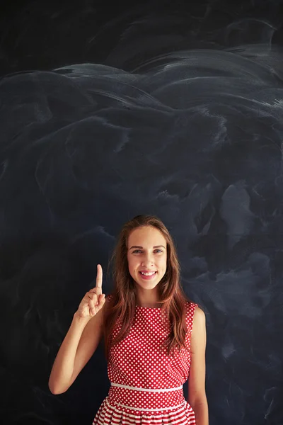 Young pretty girl standing and showing forefinger against blackb — Stok fotoğraf