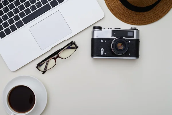 Laptop, brillen, camera, hoed en een kopje koffie op witte sur — Stockfoto