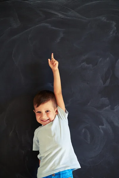 Small boy pointing upwards with forefinger of stretched arm agai — Stock Photo, Image