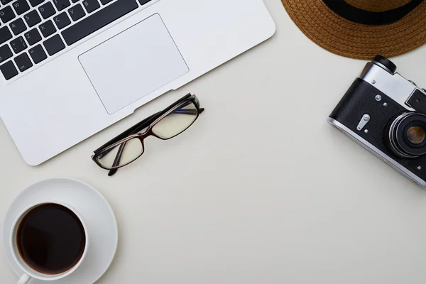 Vista superior do laptop, câmera, óculos, chapéu e uma xícara de café — Fotografia de Stock