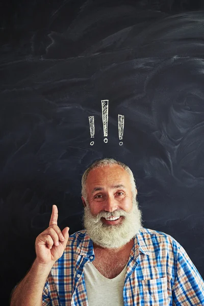 Old man pointing up against blackboard with exclamation mark ins — Stock Photo, Image
