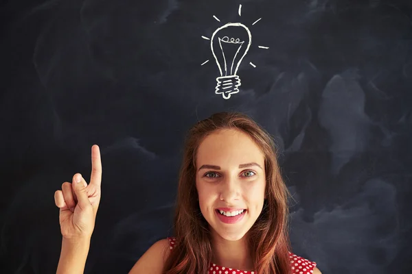 Smiling girl showing the concept of new idea with chalk drawing — Stock Photo, Image