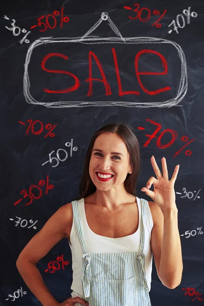 Giovane donna mostrando segno ok posa contro annuncio vendita — Foto Stock
