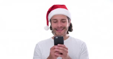 Beyaz arka planda cep telefonu kullanan Noel Baba şapkalı adam.