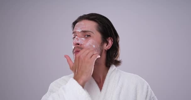 Uomo in accappatoio applicare la crema sul viso — Video Stock