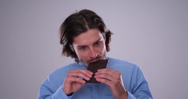 Fou homme manger chocolat bar sur fond blanc — Video