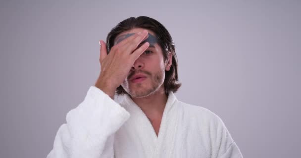 Hombre en albornoz aplicando mascarilla de barro — Vídeos de Stock