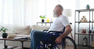 Evde tekerlekli sandalyede oturan engelli yaşlı adam.