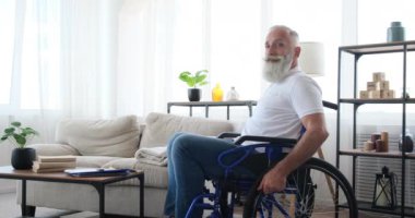 Evde tekerlekli sandalyede oturan engelli yaşlı adam.